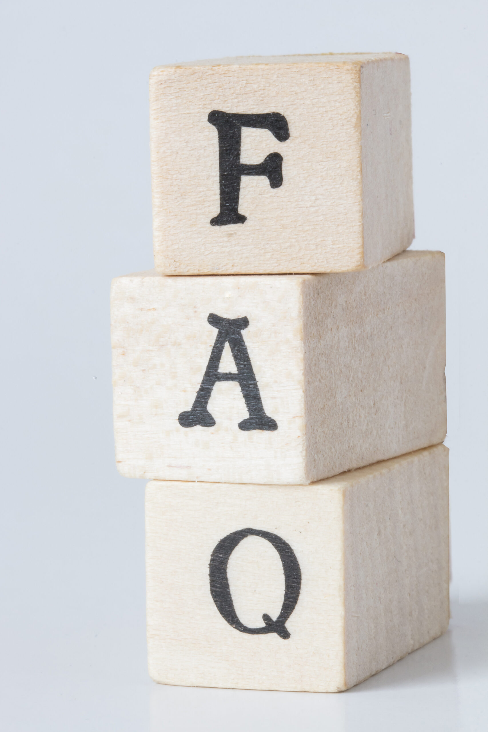 Three wooden blocks stacked vertically, each with a black letter on one side, spelling "FAQ" from top to bottom, against a plain white background.